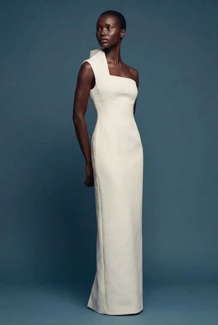 Modelo de corpo inteiro com vestido longo off-white de ombro único em fundo azul-petróleo, lookbook gerado por IA
