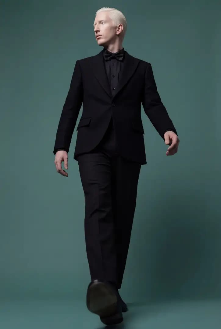 Modelo de terno preto caminhando em fundo verde-petróleo, lookbook gerado por IA